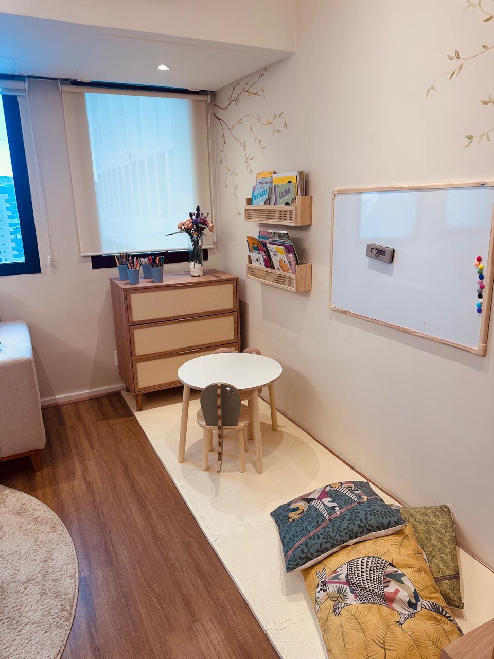 Cantinho infantil com mesinha, livros e mural de árvore